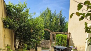 A patio area with a table and chairs, surrounded by gravel and greenery. - Apartment with private courtyard and parking in Sarlat town center (Sarlat-la-Canéda)