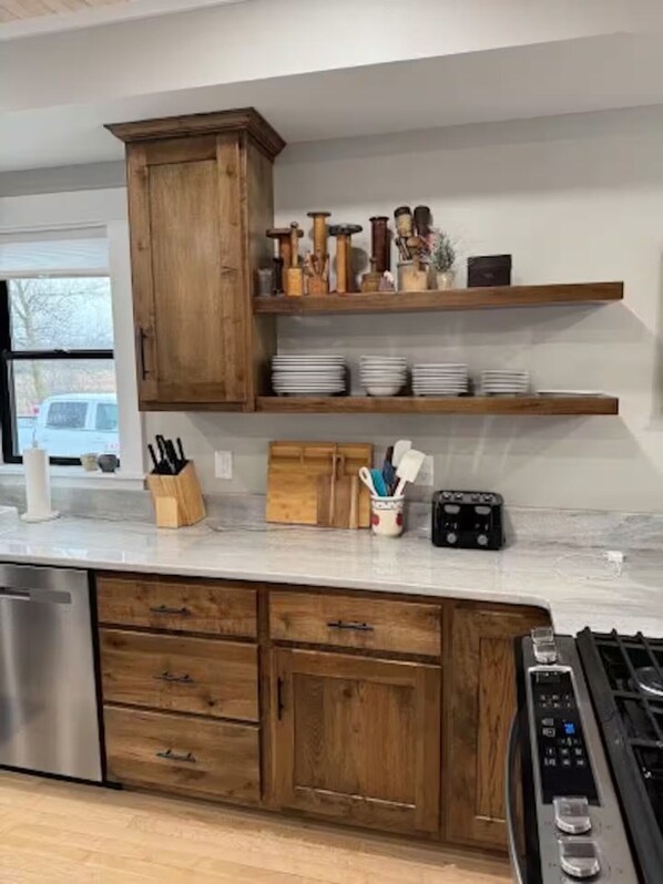 A modern kitchen with wooden cabinets, a marble countertop, and stainless steel appliances.
