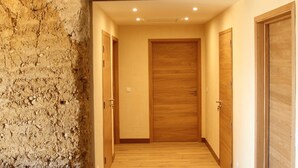 A hallway with wooden flooring, a stone wall, and wooden doors. - La ferme de Berlioz (La Cote-Saint-Andre)