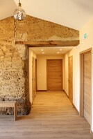 A hallway with wooden flooring, a stone wall, and wooden doors.
