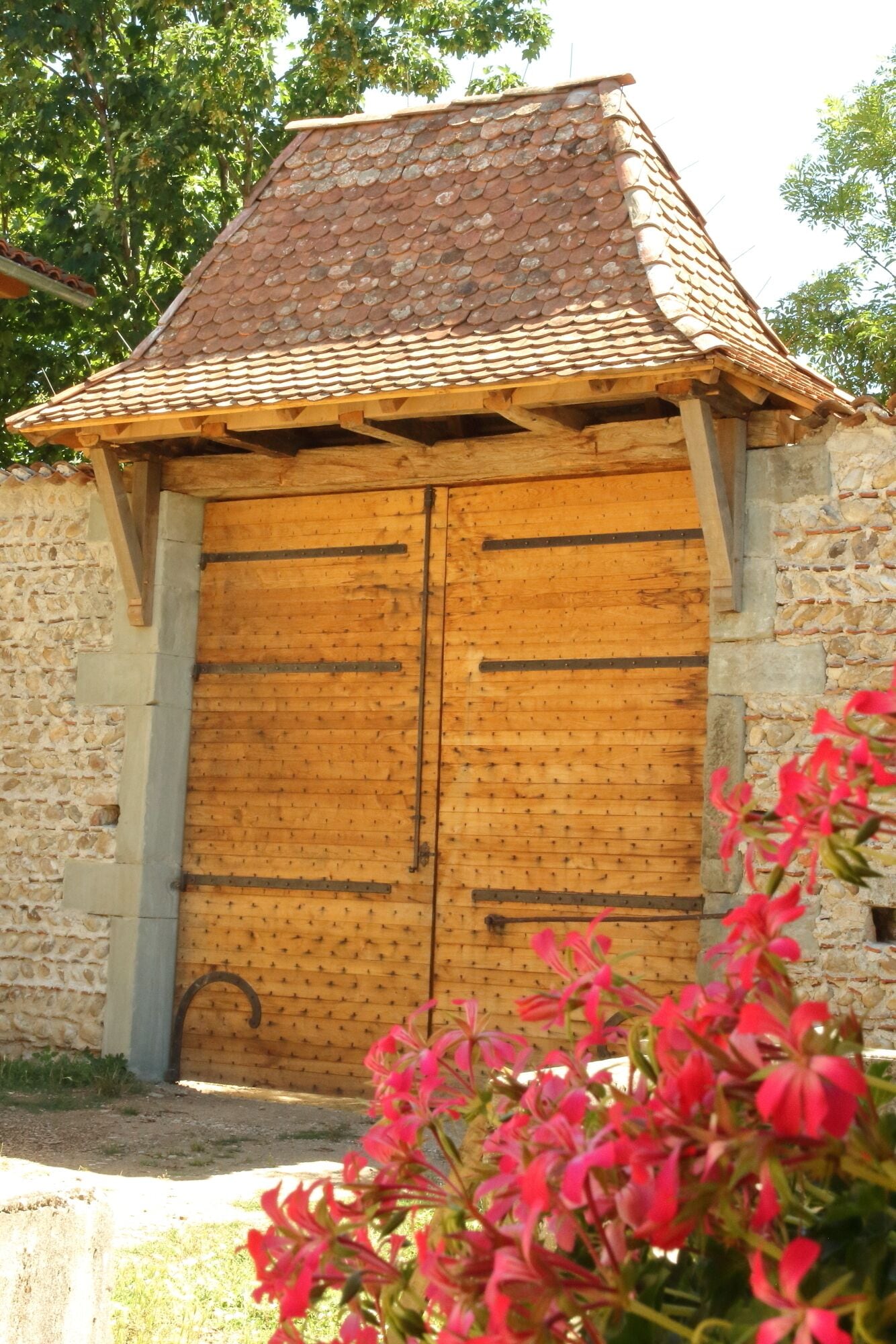 A rustic wooden building with a tiled roof and a large wooden door.
