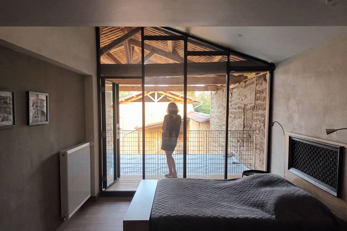 A bedroom with a large bed, a view of the outside, and a balcony.