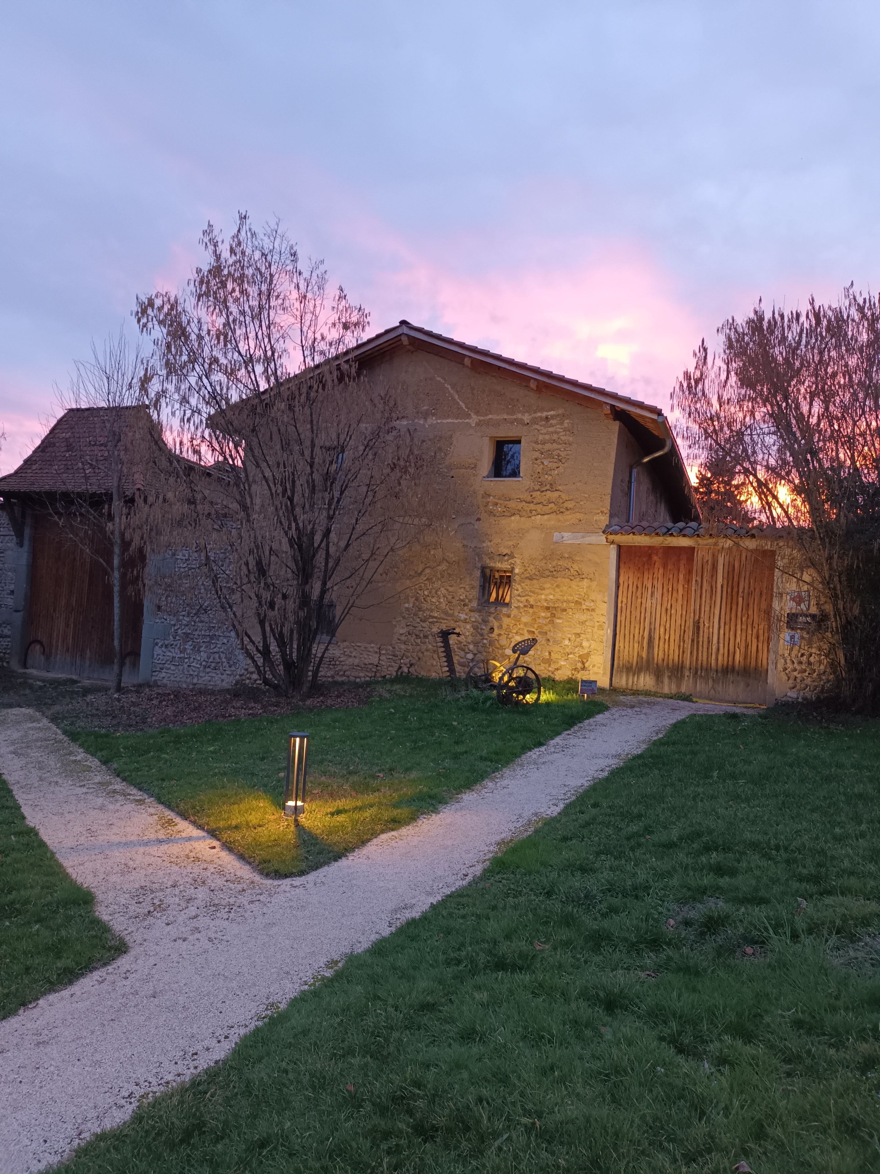 A rustic house with a stone facade, a wooden garage door, and a bicycle parked outside.