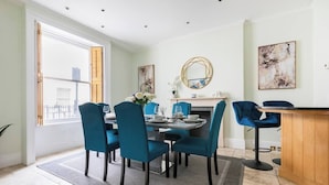 Un comedor con una mesa redonda, sillas color turquesa y una barra de madera.