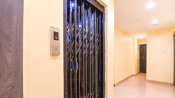 A hallway with a metal gate, a digital elevator control panel, and a tiled floor.