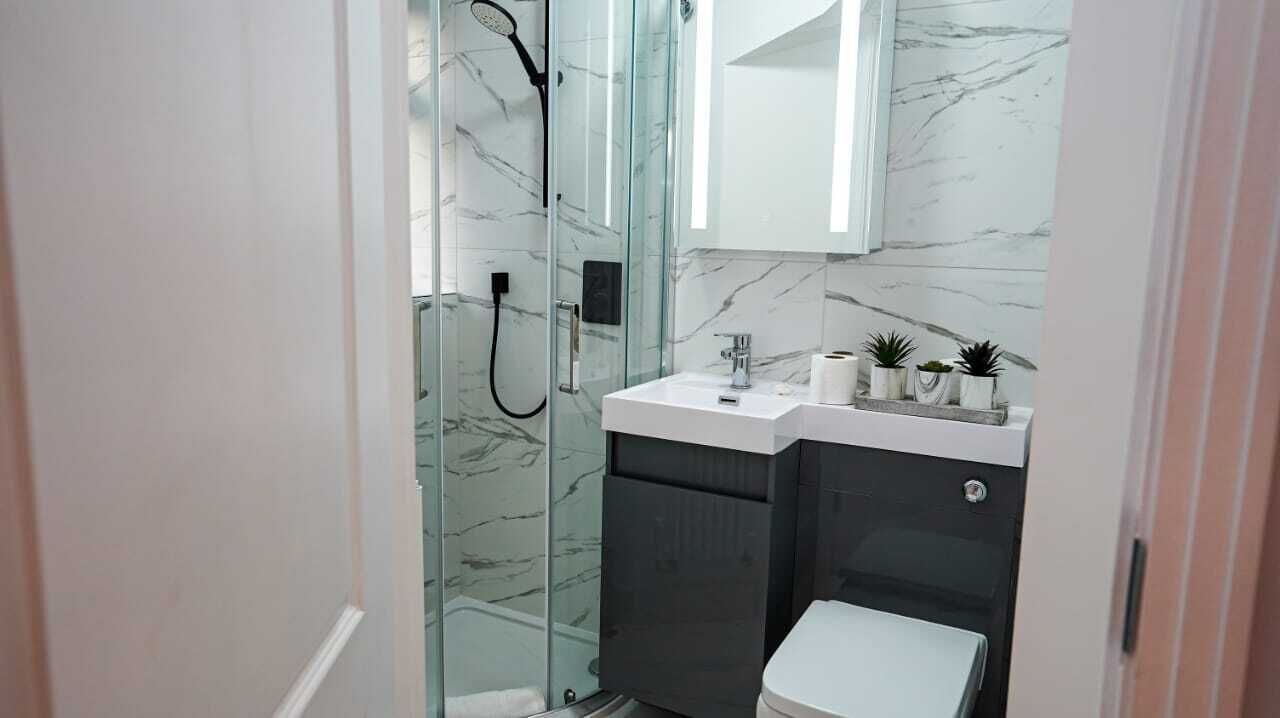 A compact bathroom with a glass-enclosed shower, a white sink, and a toilet.