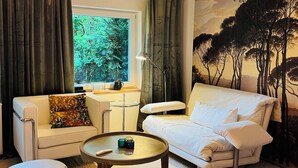Una sala de estar moderna con un sofá blanco, una mesa de centro redonda y un ventanal con cortinas.
