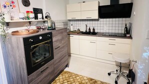 Una cocina moderna con horno empotrado, armarios blancos y una campana extractora negra.