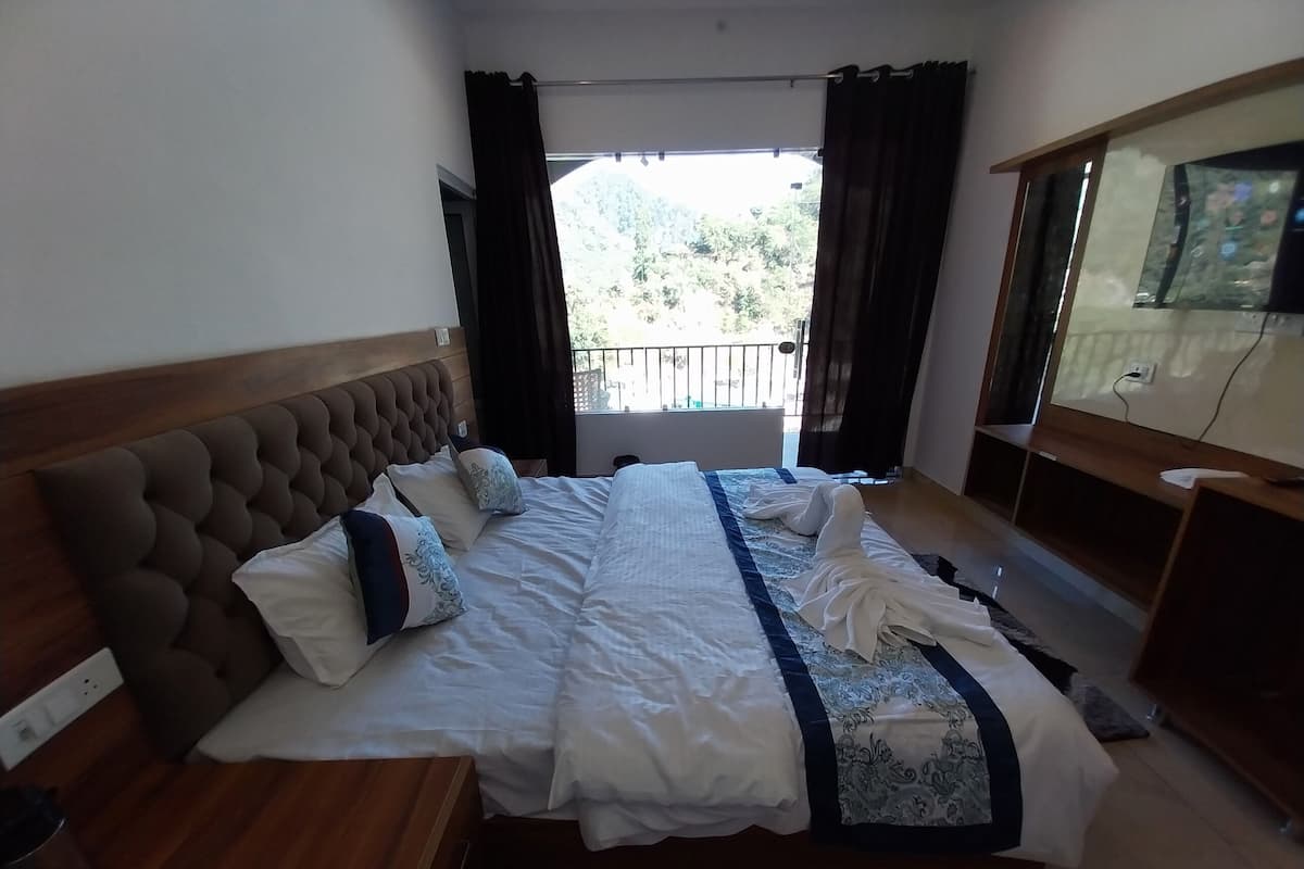 Une chambre d’hôtel avec un grand lit, une tête de lit en bois et un balcon agrémenté de rideaux.