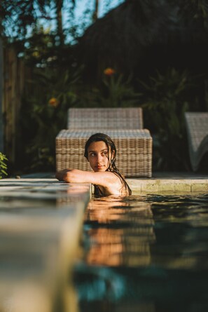 A person in a swimming pool with wicker lounge chairs in the background. - The Grand Haveli Resort By Atya Hotels (Mohan Chatti)