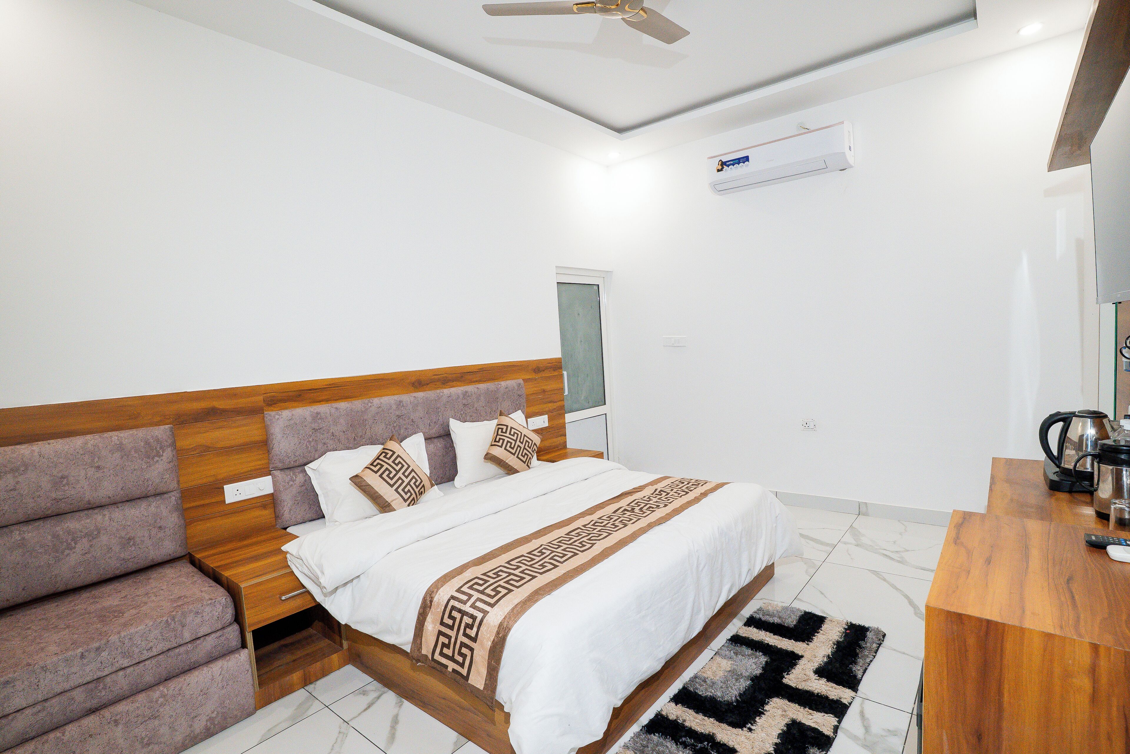 A modern bedroom with a wooden headboard, a bed with a patterned bedspread, a sofa, and a coffee table.