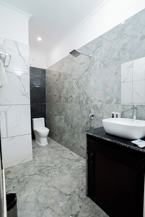 A bathroom with a white toilet, a black sink, and a shower. - The Grand Haveli Resort By Atya Hotels (Mohan Chatti)