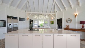 Una cocina moderna con una isla grande, armarios blancos y un techo abovedado.
