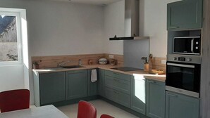 A compact kitchen with green cabinets, a sink, a stove, and a microwave. - Country house in the heart of Périgord Noir in Rouffignac  (Rouffignac-Saint-Cernin-de-Reilhac)