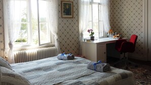 A hotel room with a bed, a desk, a chair, a radiator, and a window with curtains. - Wallin House  (Värmlands län)