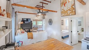 Un salón espacioso con chimenea, vigas de madera y un cuadro grande.