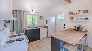 Una cocina con electrodomésticos blancos, encimera de madera y ventana con vista a zonas verdes.