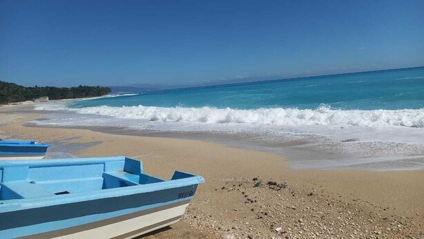 A beach with a boat and a clear view of the ocean.