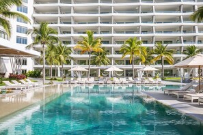 A modern hotel with a large pool, palm trees, and sun loungers. - 2BD Oceanview Suite Garza Blanca Cancun (Cancun)