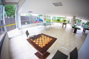 Amplio espacio interior con un gran tablero de ajedrez, una mesa de ping pong y vistas al exterior.