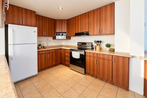A kitchen with wooden cabinets, a white refrigerator, a stove, and a microwave. - DP3 4-bedroom apartment with WiFi and great views (Ciudad de Guatemala)