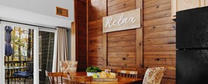A dining area with wooden walls, a sign that says "Relax Unwind & ENJOY", and a view of trees outside. - Cheerful 3-Bedroom Cabin in amazing Wintergreen Resort (Wintergreen Resort)