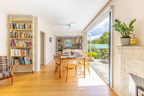Una habitación amplia con comedor, estantería y vistas al exterior.