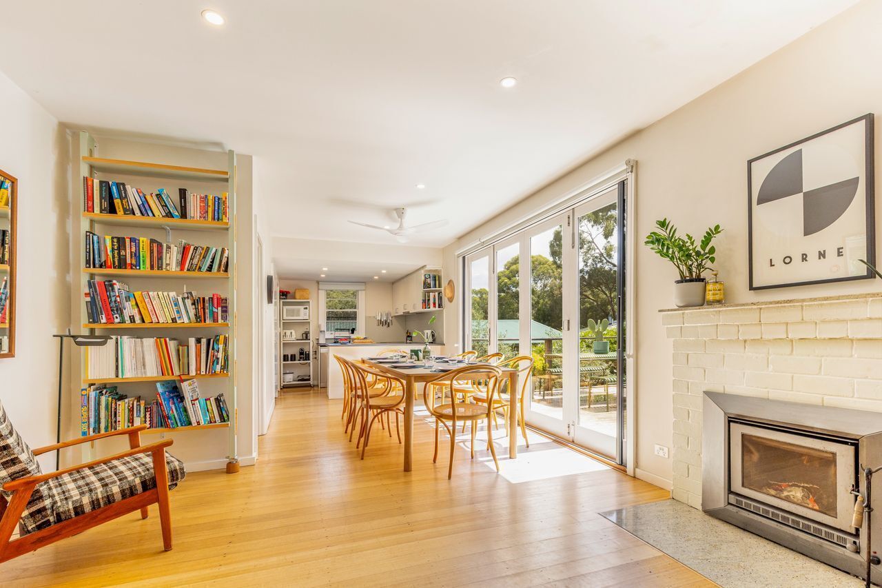 A spacious living area with a fireplace, a dining table, and a bookshelf filled with books.