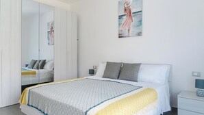 Een moderne slaapkamer met een groot bed, een garderobe met spiegel en een schilderij aan de muur.