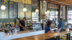 Un caffè con una bacheca dei menu, un barista e dei clienti.