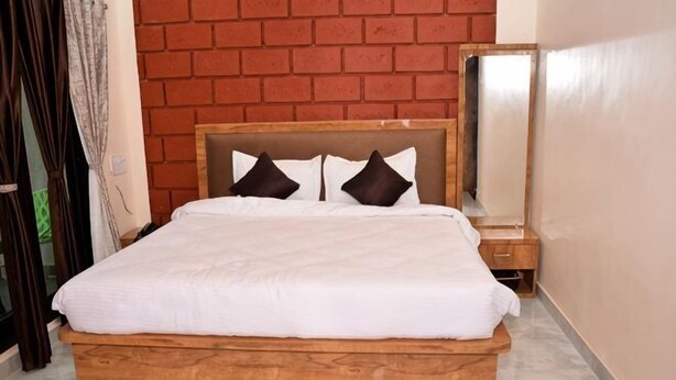A bed with a wooden frame, white bedding, and two pillows. - The Blissview Resort (Diveagar)