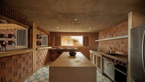 A kitchen with brick walls, a central island, and stainless steel appliances. - Mariana Uno · Luxury · Exclusive Bay Oaxaca (Puerto Escondido)