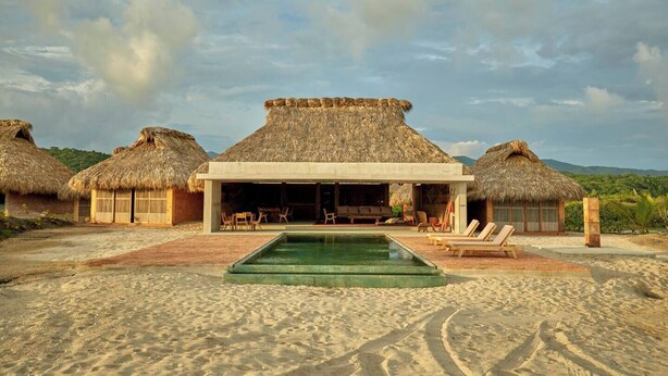 A beachfront property with thatched-roof huts, a swimming pool, and a patio area. - Mariana Uno · Luxury · Exclusive Bay Oaxaca (Puerto Escondido)