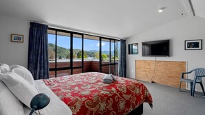 Een hotelkamer met een groot bed, een televisie en uitzicht op de bergen.