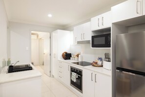 A modern kitchen with white cabinetry, a stainless steel refrigerator, a microwave, and a built-in oven. - Smart Suites Self Check-in Apartments - 16 Freney (Rocklea)