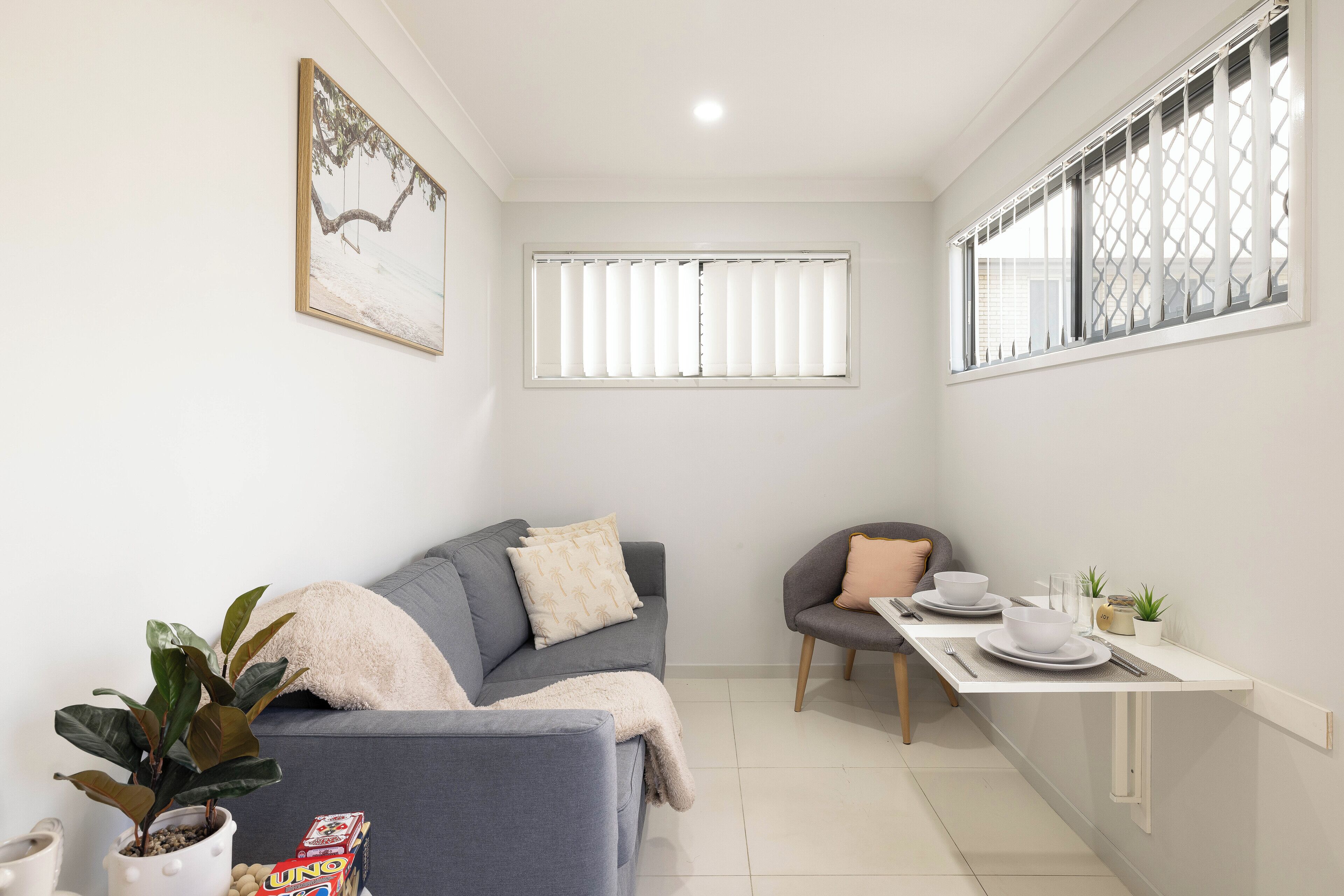 A compact living space with a sofa, a dining table, and a small kitchen area.