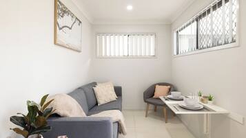 A compact living space with a sofa, a dining table, and a small kitchen area.