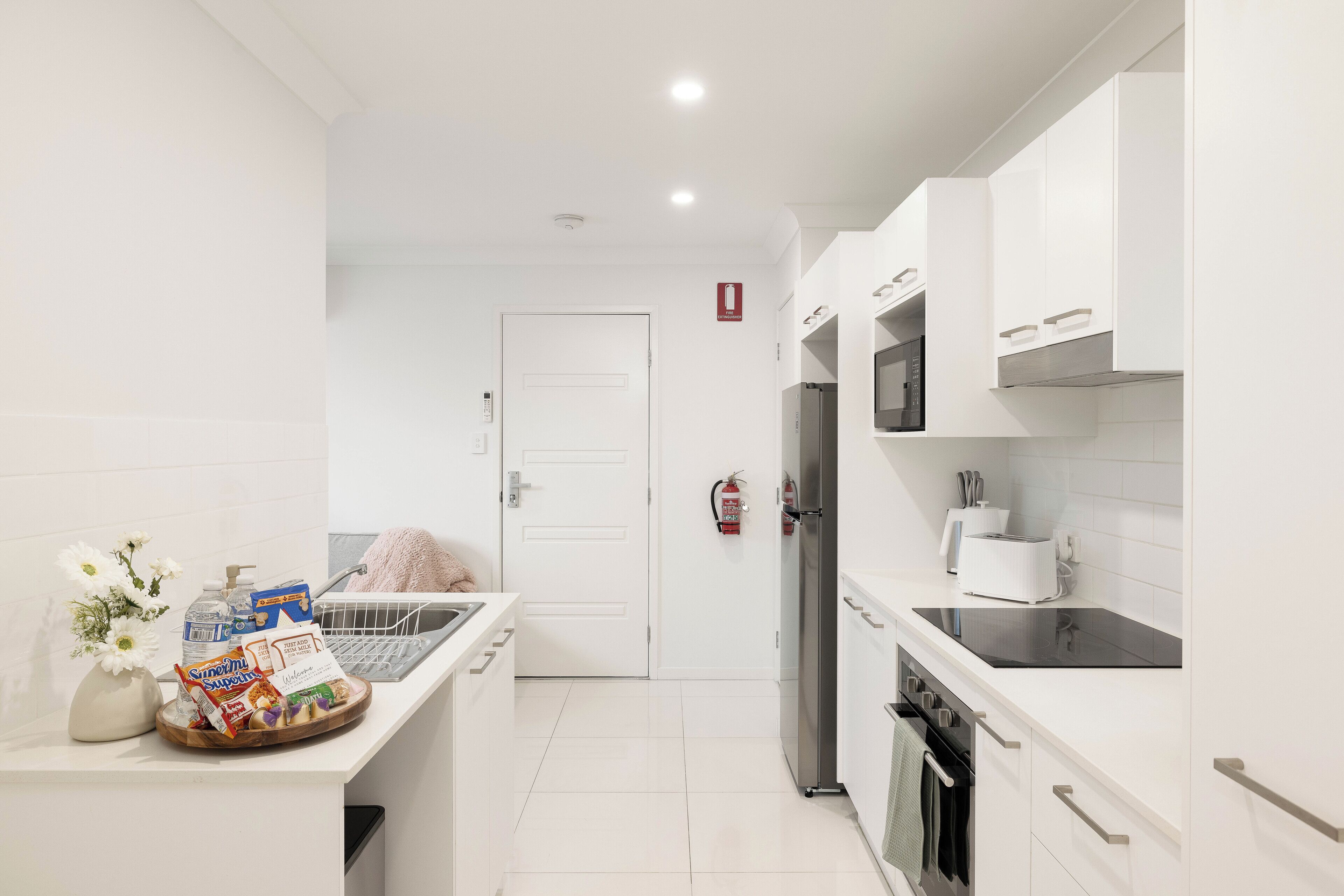 Una cocina moderna con armarios blancos, un refrigerador de acero inoxidable y una encimera negra.