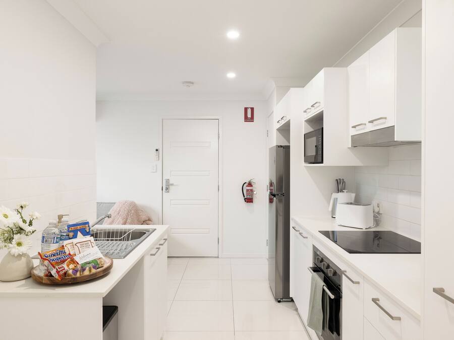 Una cocina moderna con armarios blancos, un refrigerador de acero inoxidable y una encimera negra.