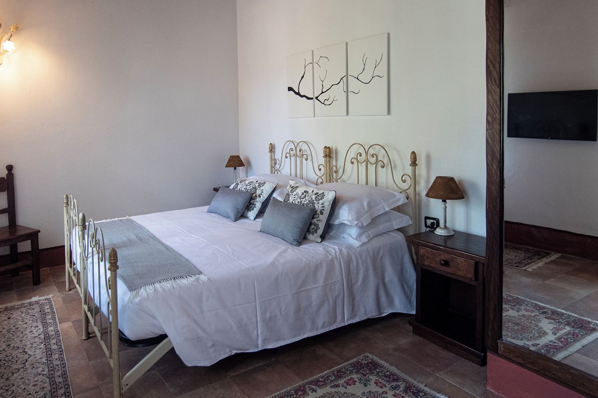 A neatly arranged bedroom with a bed, bedside tables, a chair, and wall art.