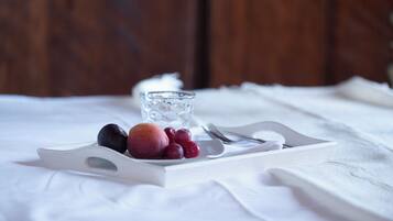 Una bandeja con frutas y un vaso sobre un mantel blanco.