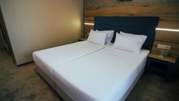 Un lit double avec du linge de lit blanc dans une chambre d’hôtel.