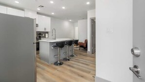 Una cocina moderna con una isla central, taburetes de bar y piso de madera.