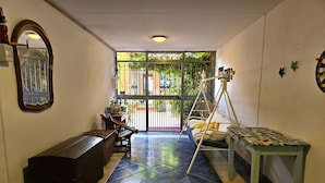 A room with a bed, a desk, a chair, a mirror, and a window with a view of greenery.