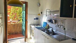 A compact kitchen with white cabinets, a stainless steel sink, and a hanging rack for utensils.