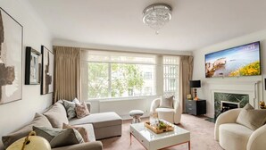 A modern living room with a white sofa, a glass coffee table, and a fireplace. - Large Lux 5 Bedroom Townhouse by Mayfair (London)