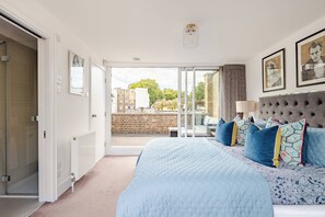 A bedroom with a large bed, a sliding glass door to a balcony, and a view of the cityscape.
