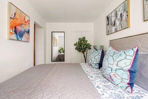 Un dormitorio con una cama grande, un espejo y dos cuadros en la pared.