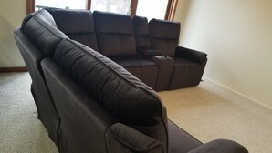 A sectional sofa with a chaise lounge in a room with carpeted flooring and a window. - Charming 1-bedroom apartment in peaceful Elma with WiFi, AC (Elma)