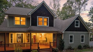 A two-story house with a front porch, a deck, and a small attached garage.